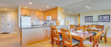 A modern kitchen with wooden cabinets, a central island, and a dining area with wooden chairs and a table set for four.
