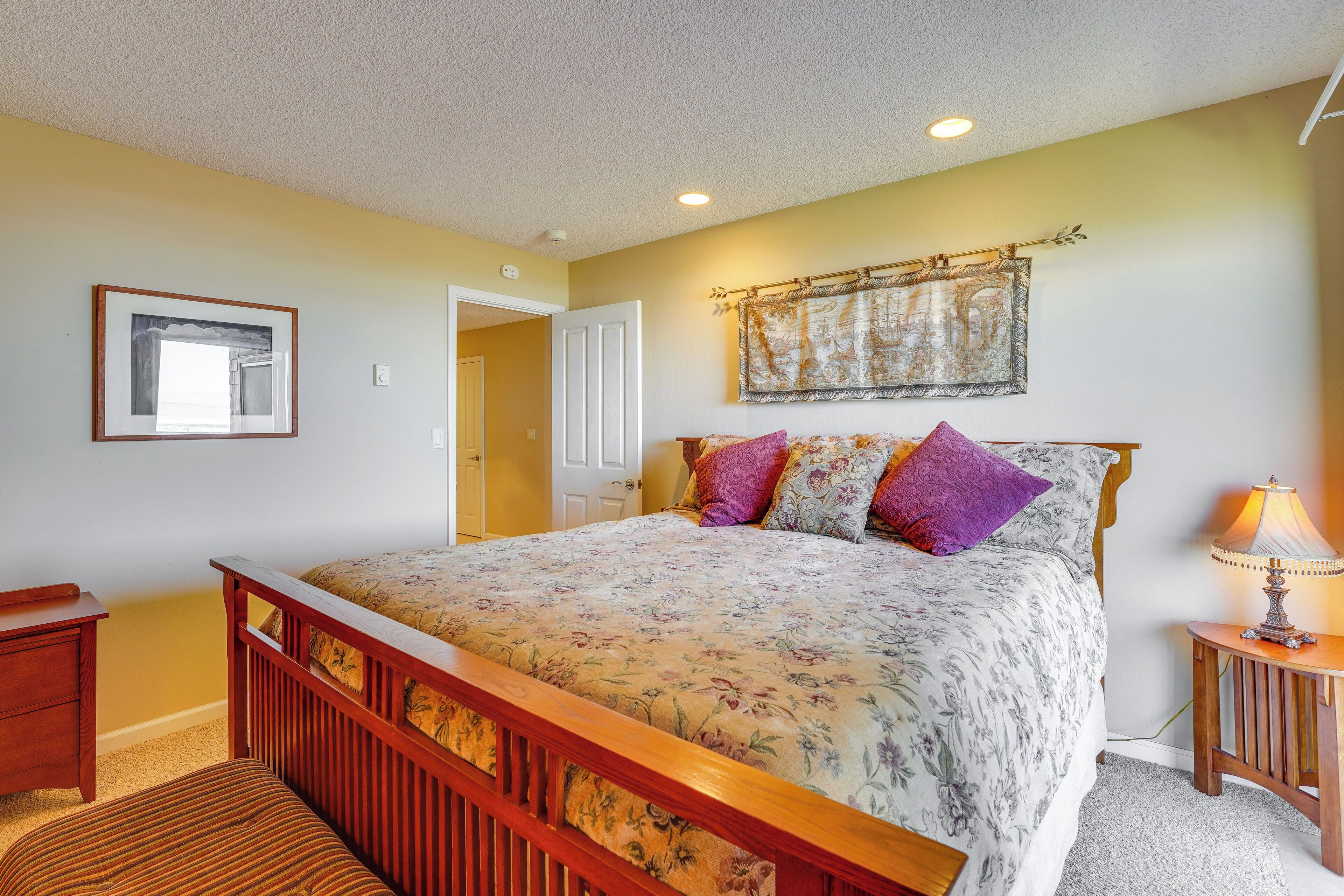A bedroom with a wooden bed, a nightstand, a lamp, and a framed picture on the wall.