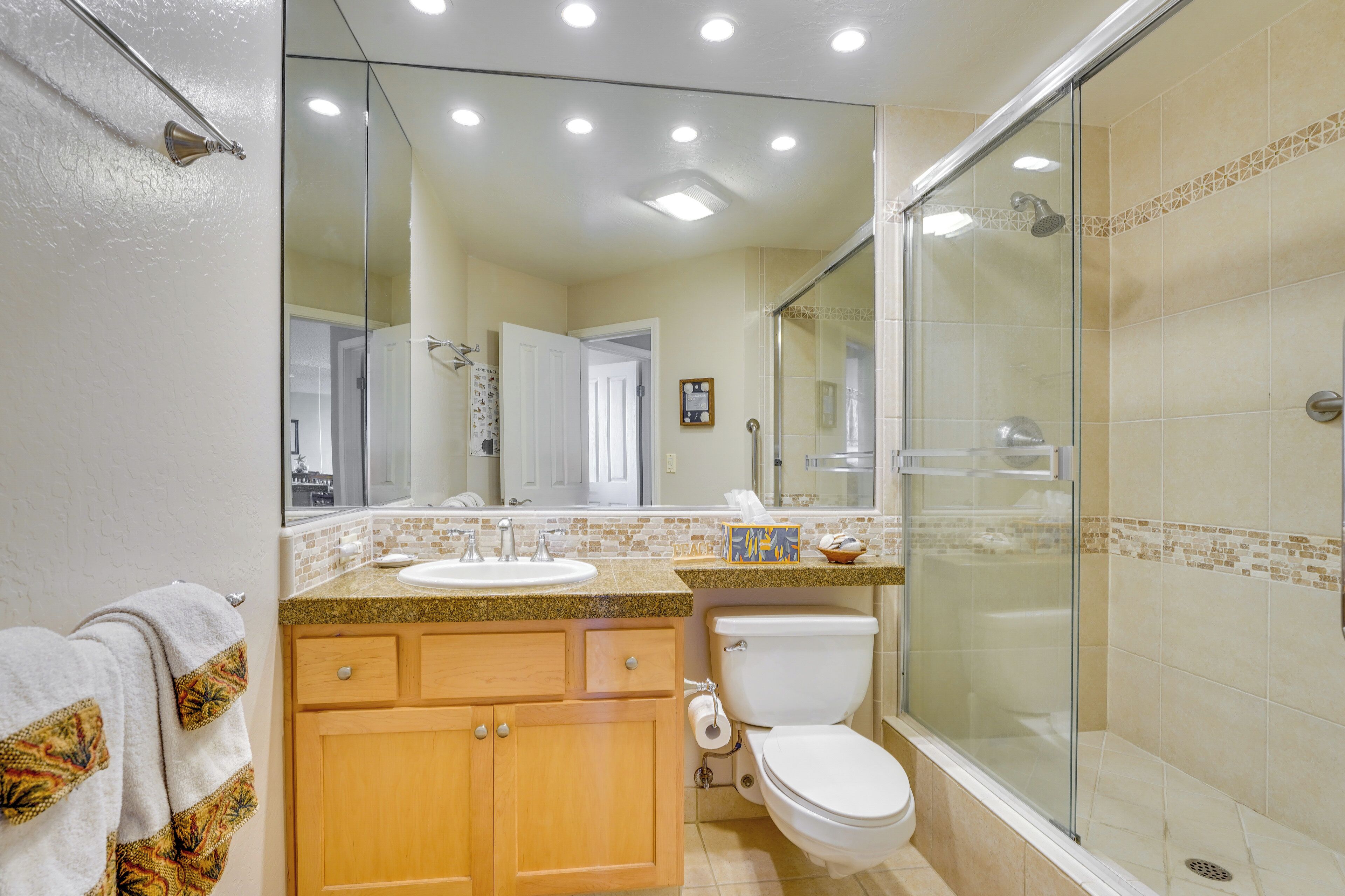 A bathroom with a glass shower enclosure, a sink, and a toilet.