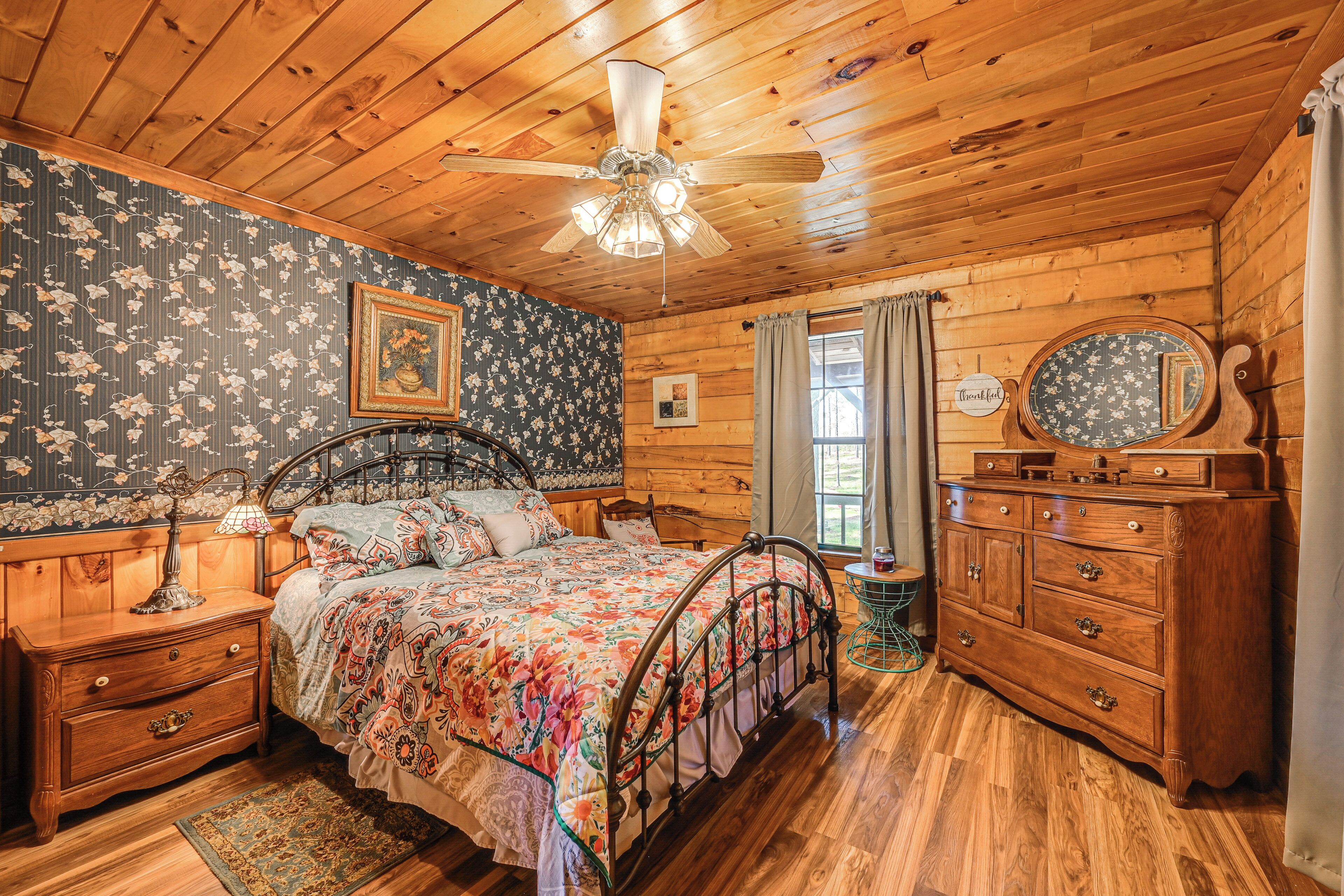 Een houten slaapkamer met een bed, een dressoir en een plafondventilator.