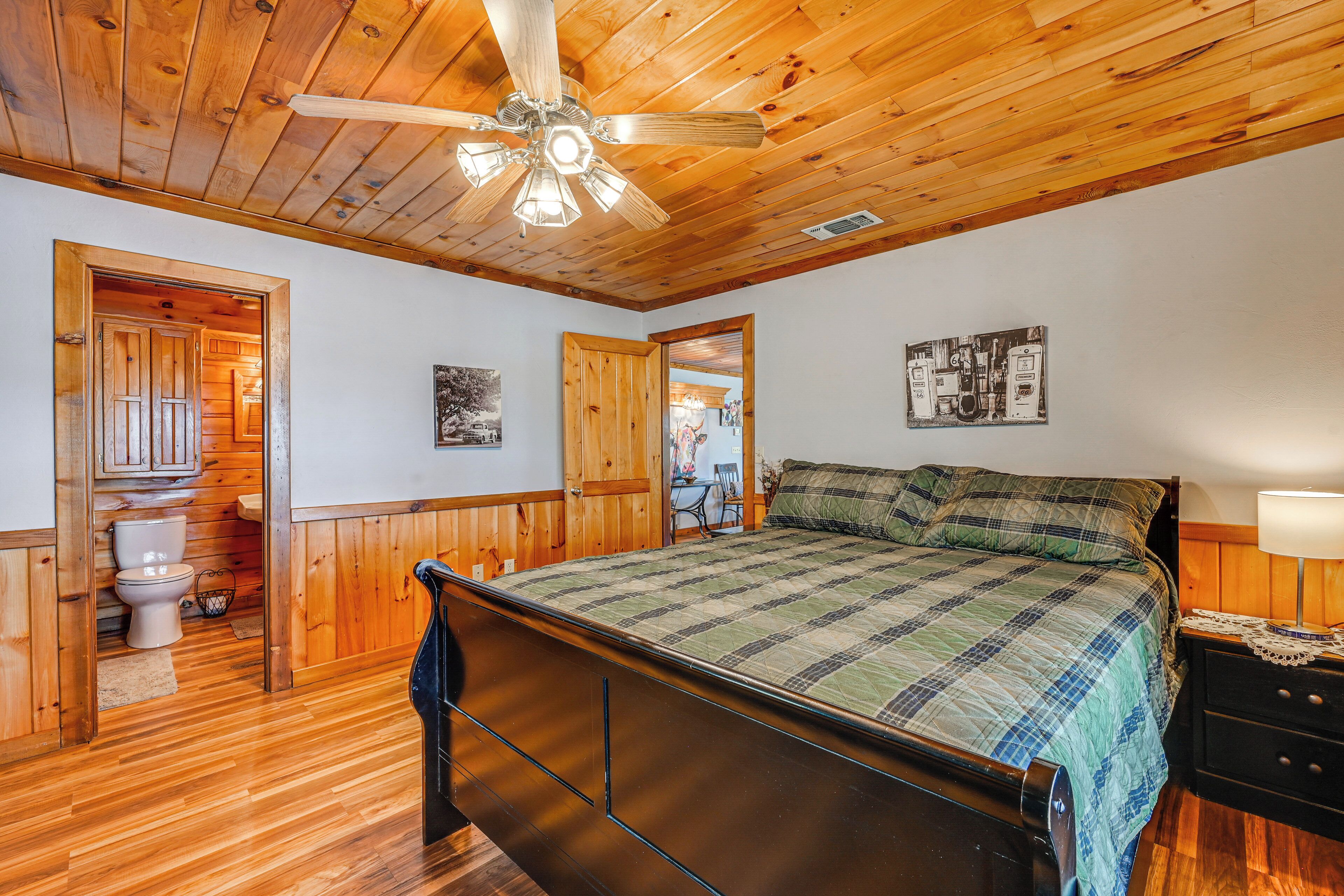Une chambre avec un plafond en bois, un lit recouvert d’une courtepointe, une table de chevet et un ventilateur de plafond.