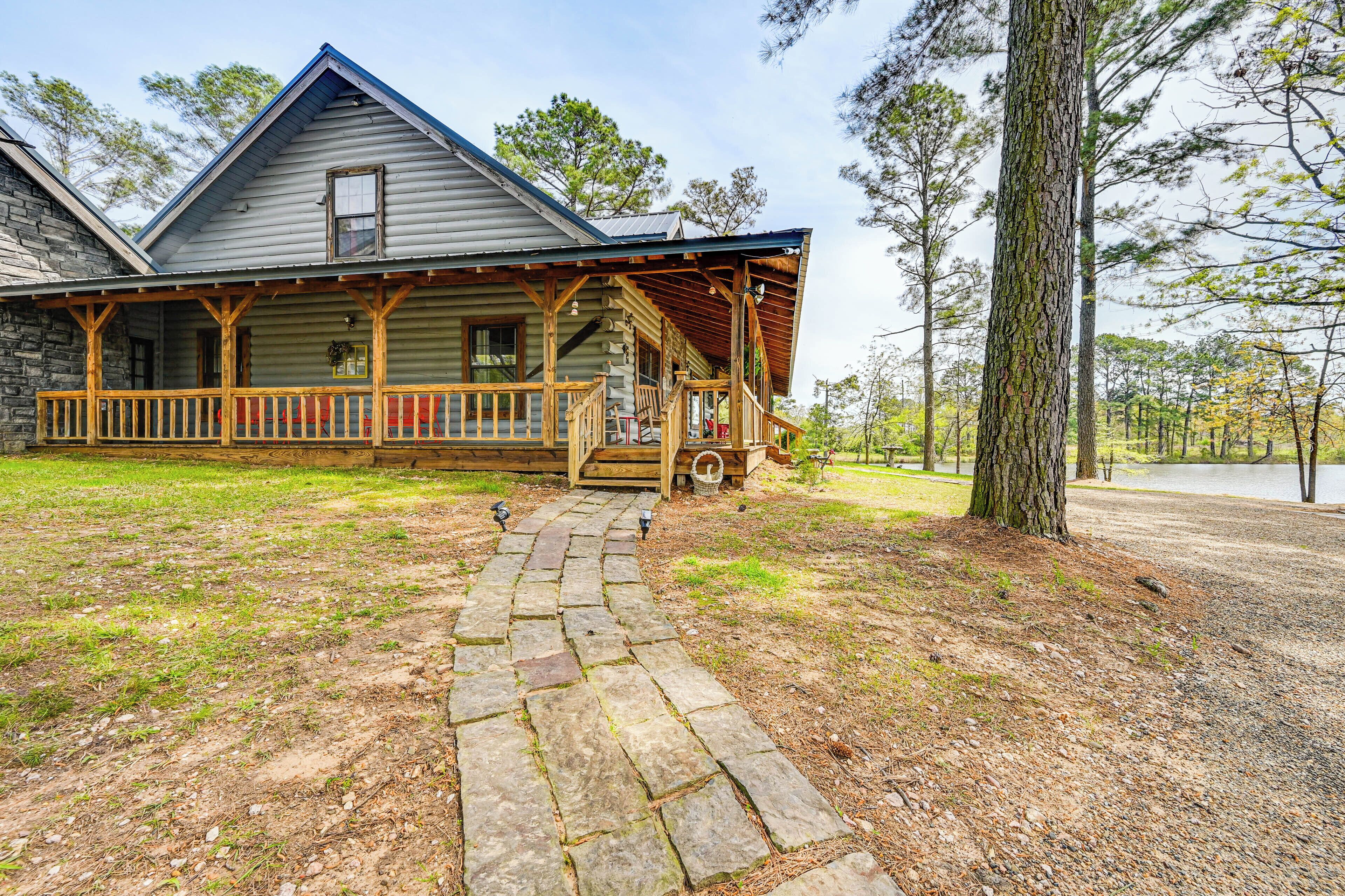 A rustic log cabin with a stone pathway leading to a wooden porch. - Broken Bow Cabin w/ Hot Tub & Fishing On-site! (Broken Bow)