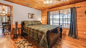 A wooden cabin bedroom with a bed, a small table, and a chair. - Broken Bow Cabin w/ Hot Tub & Fishing On-site! (Broken Bow)