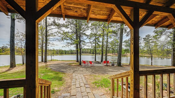 A wooden deck with a stone pathway leading to a seating area by a lake. - Broken Bow Cabin w/ Hot Tub & Fishing On-site! (Broken Bow)