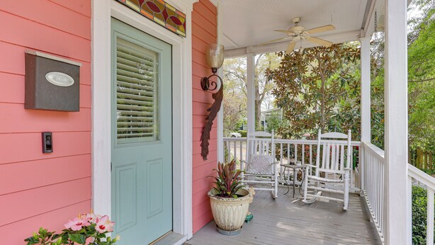 A porch with a mailbox, a door, a potted plant, and a white rocking chair. - Charming Wilmington Cottage - Walk to Downtown! (Wilmington)