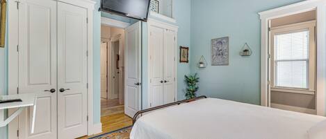 Un dormitorio con cama, televisión y un ventanal amplio.