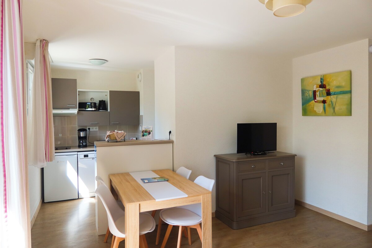 A compact living space with a kitchenette, a dining area, and a television.