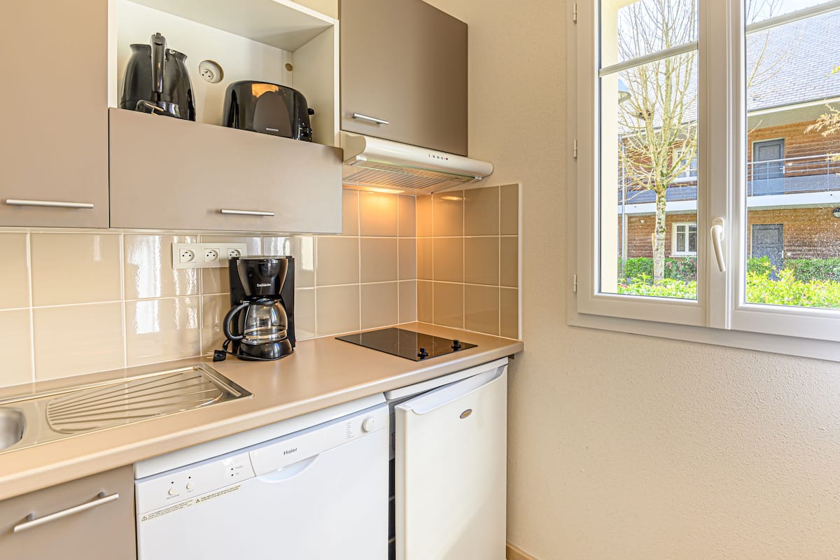 Eine kleine Küche mit Geschirrspüler, Kaffeemaschine und Toaster.
