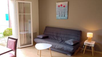 Un salon avec un canapé gris, une petite table blanche, une lampe et un tableau accroché au mur.