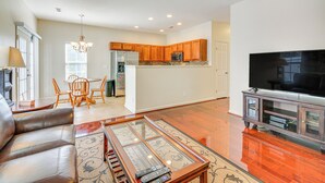 A spacious living room with a leather sofa, a glass-top coffee table, and a flat-screen TV. - Cozy Greensboro Townhome w/ Community Pool & Grill (Greensboro)