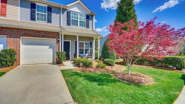 A two-story house with a front garage, a covered porch, and a well-maintained lawn with a tree. - Cozy Greensboro Townhome w/ Community Pool & Grill (Greensboro)