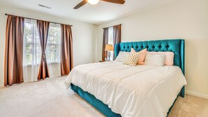 A bedroom with a large bed, a ceiling fan, and a window with curtains. - Cozy Greensboro Townhome w/ Community Pool & Grill (Greensboro)