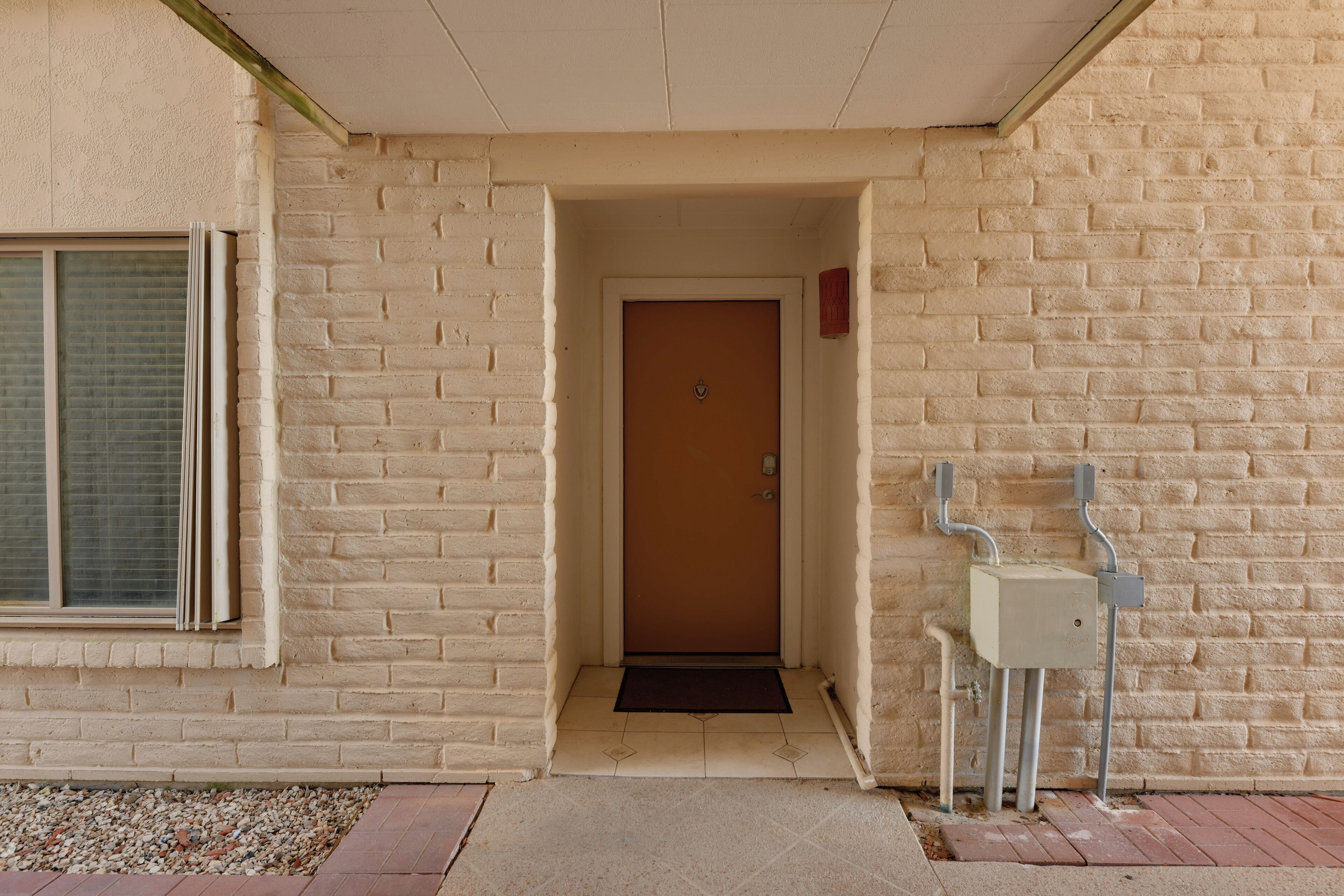 A building entrance with a door, a window, and a utility box.
