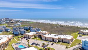Un quartier résidentiel situé sur la côte, composé de plusieurs immeubles, d’une piscine et bordé par une plage.