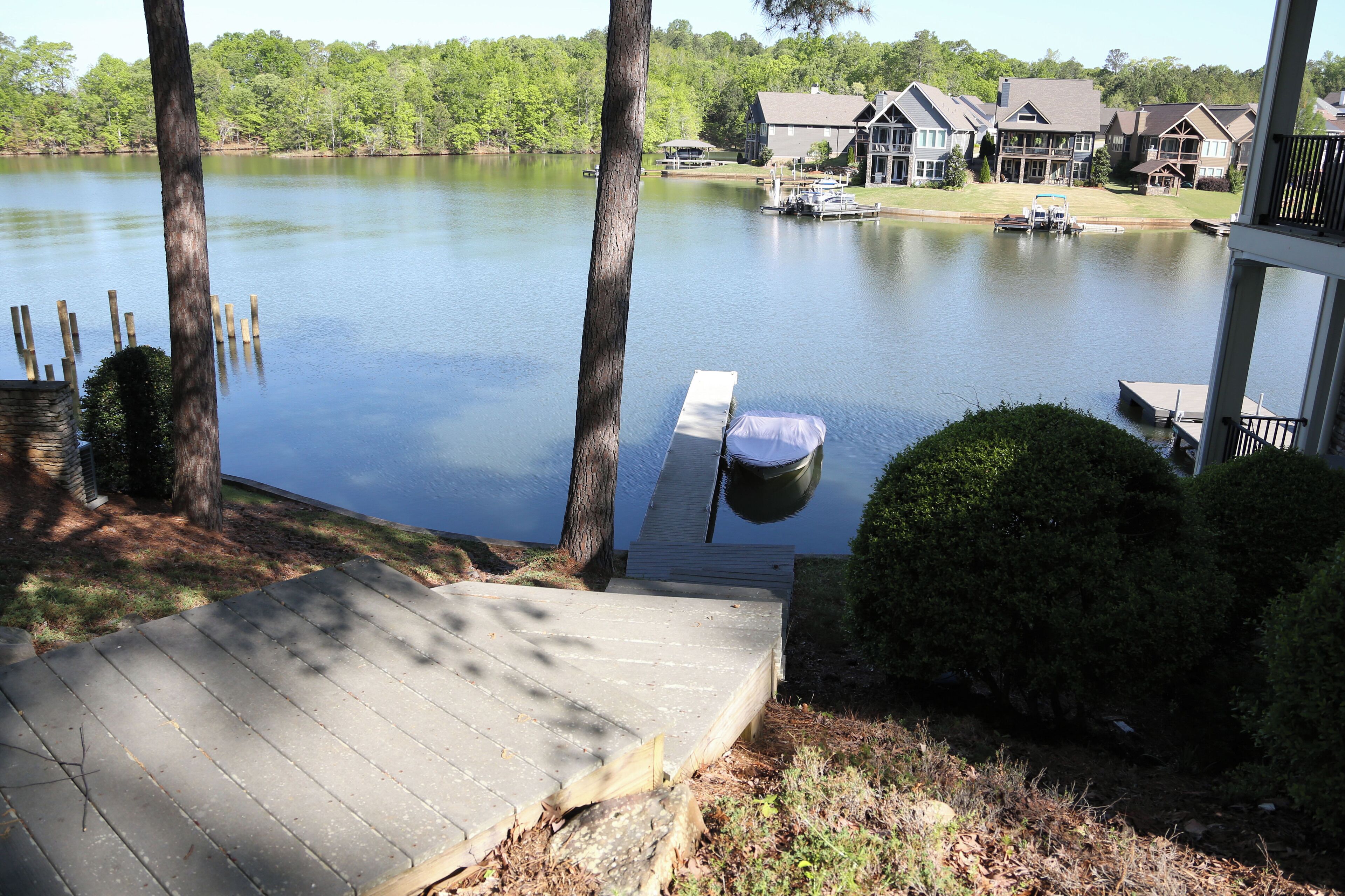 A lakeside view with a dock, a wooden deck, and houses in the background.