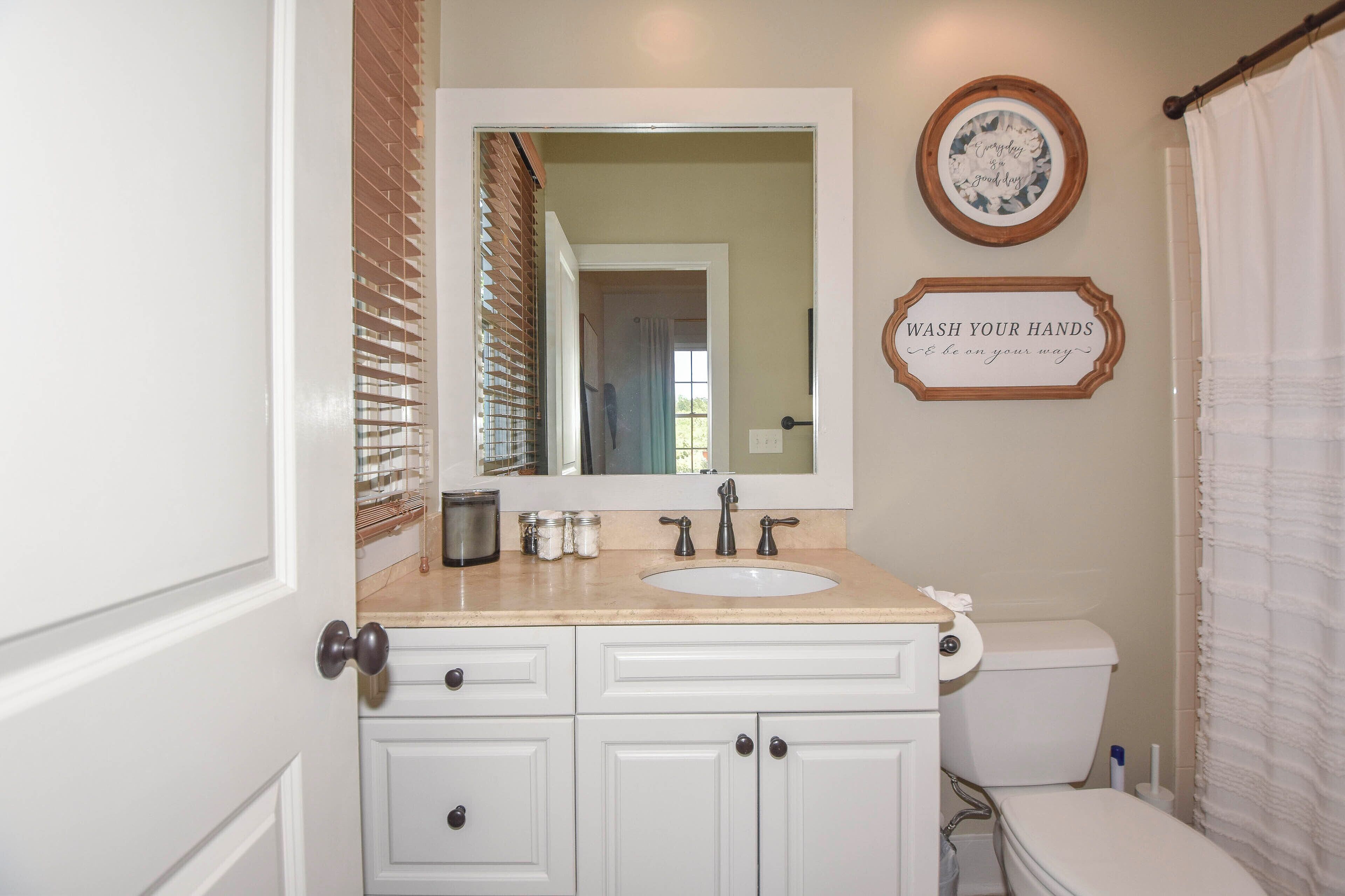 A bathroom with a white sink, a mirror, a toilet, and a shower curtain.