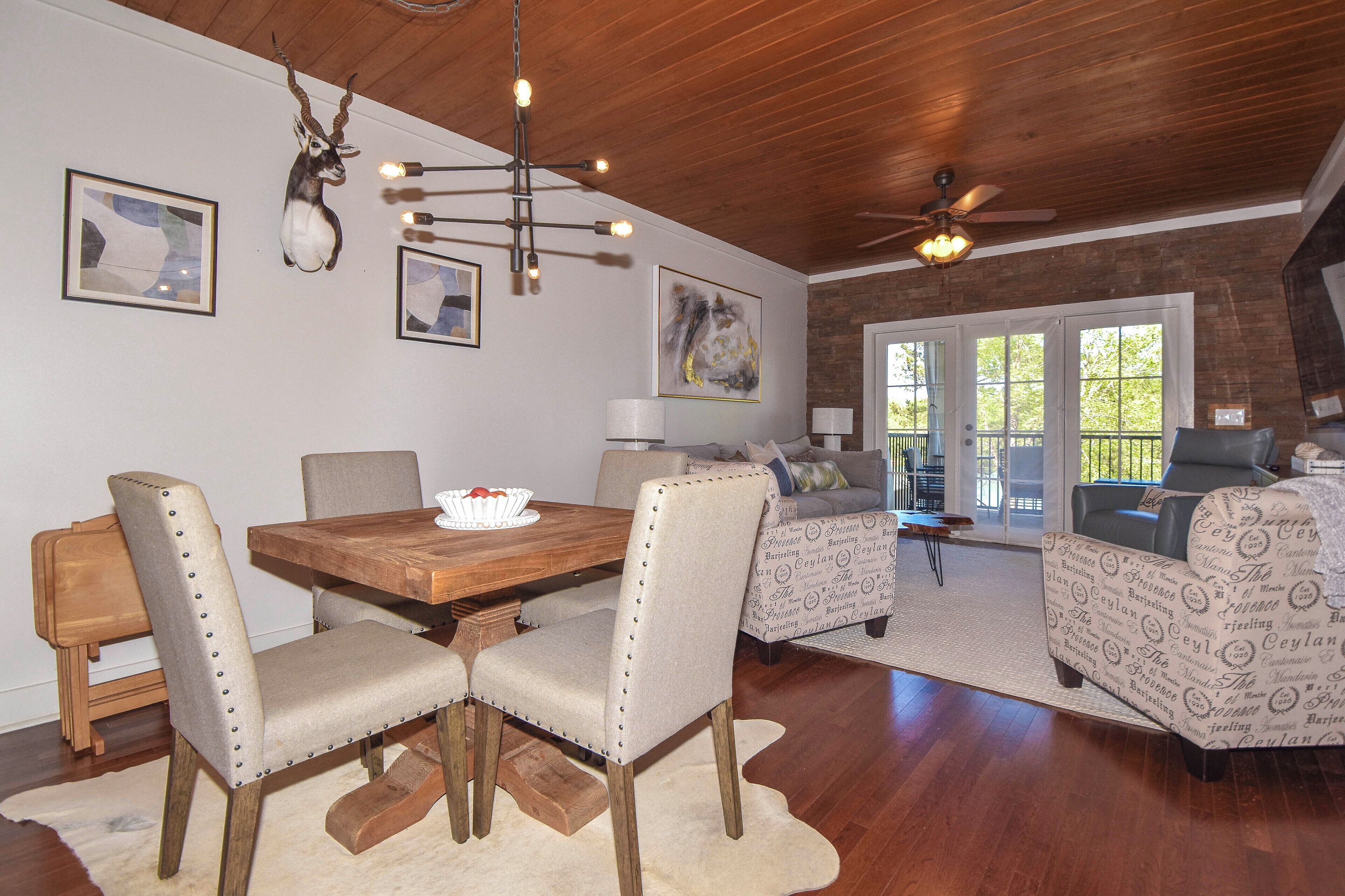 A dining area with a wooden table and chairs, a chandelier, and artwork on the walls.