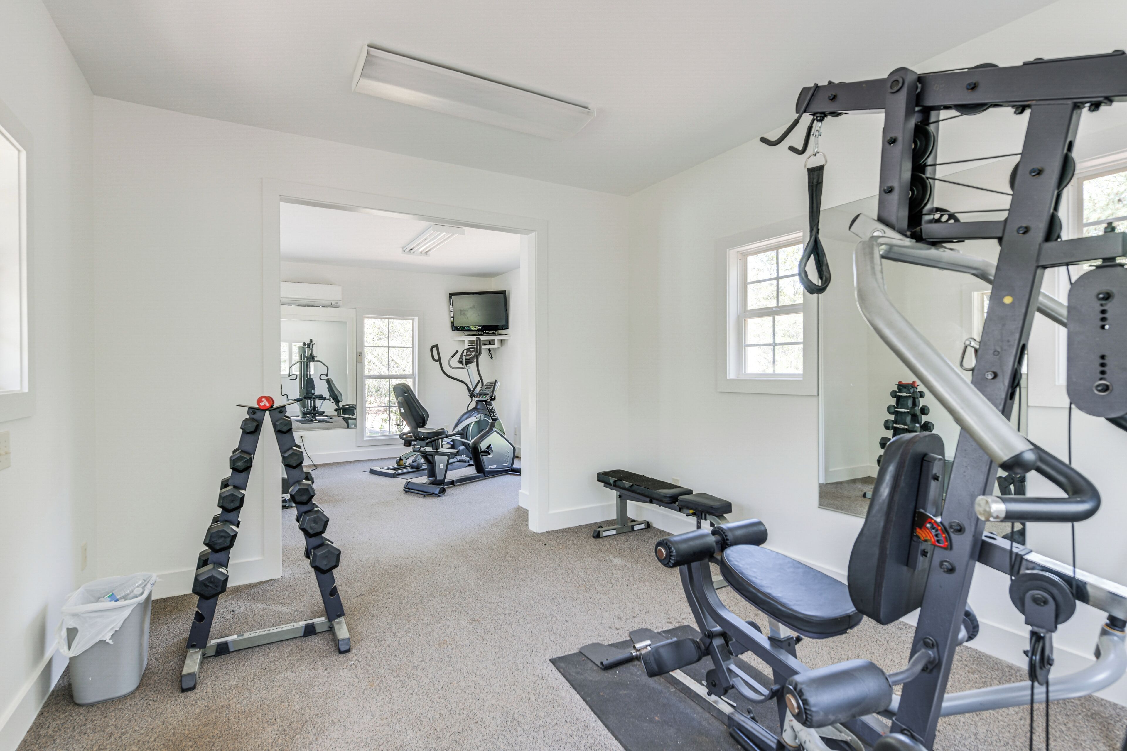 A gym with exercise equipment, a bench, and a TV on the wall.