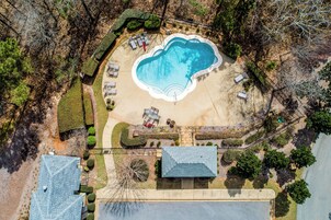 Vista aérea de una propiedad con piscina, sillas de descanso y un jardín bien cuidado.