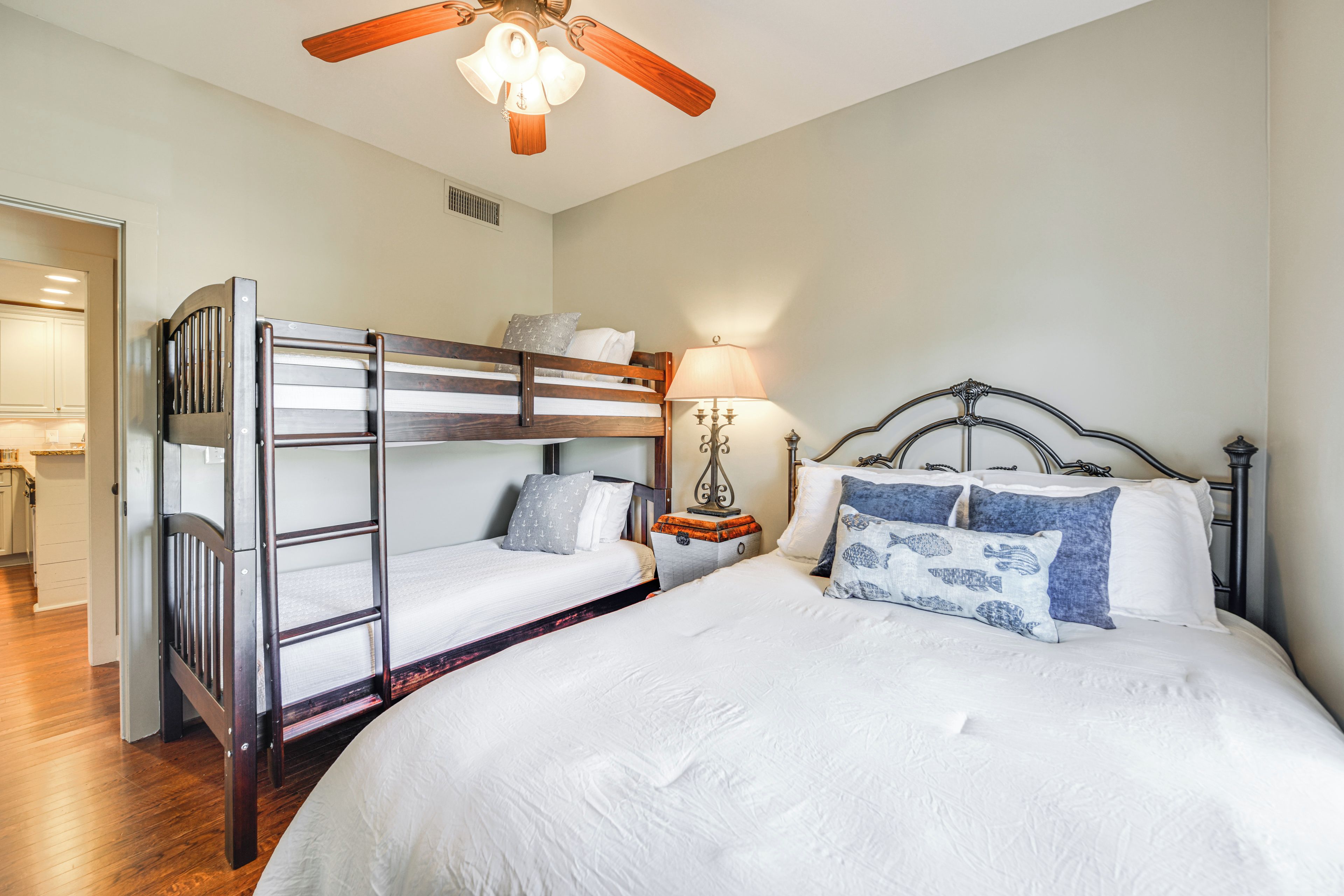 A bunk bed room with a ceiling fan, a bedside table with a lamp, and a nightstand.