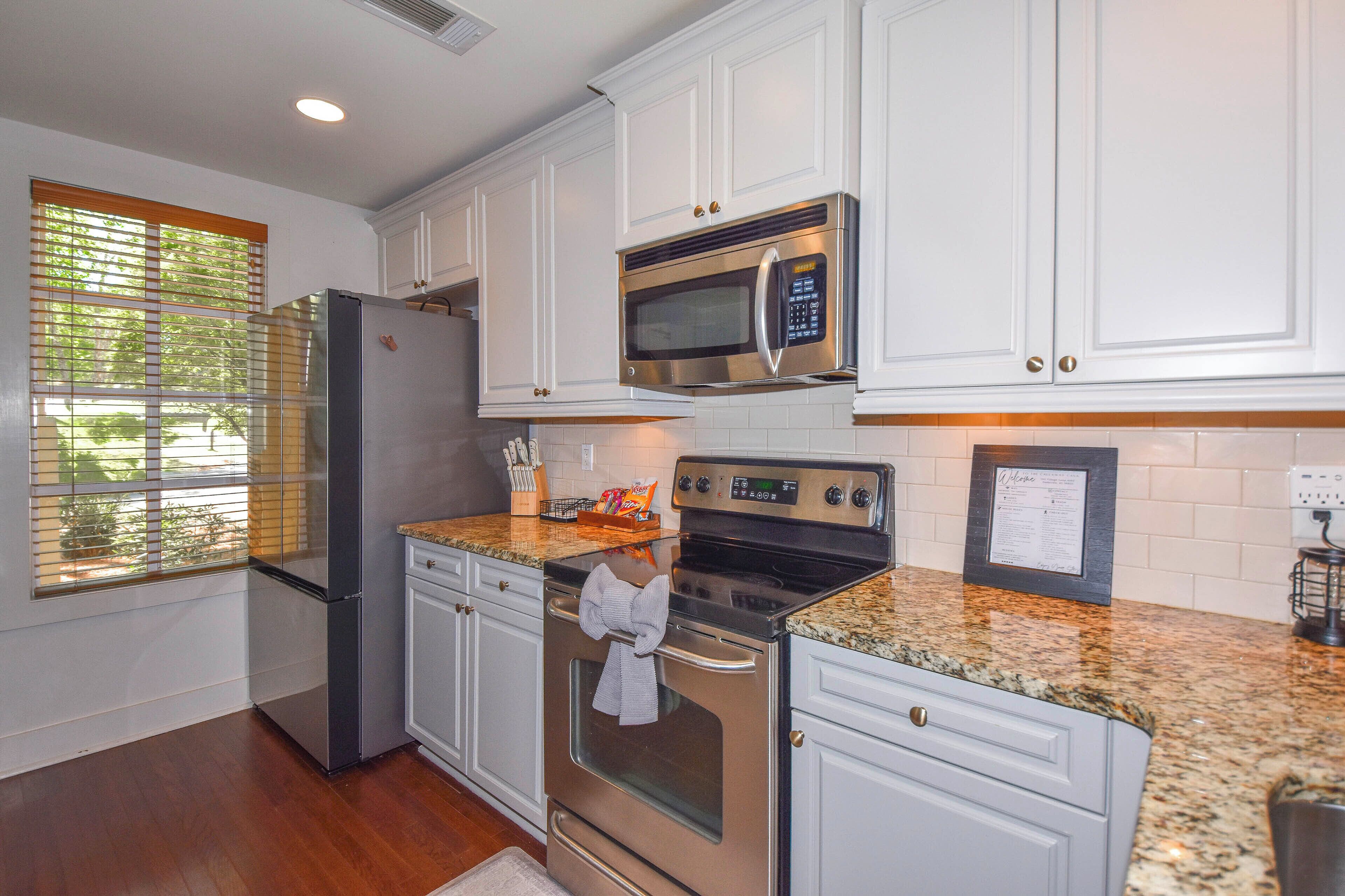 A kitchen with white cabinets, stainless steel appliances, and a granite countertop.