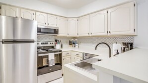 A modern kitchen with white cabinetry, stainless steel appliances, and a patterned backsplash. - Porch & Water Views: Getaway in Mallard Lakes (Selbyville)