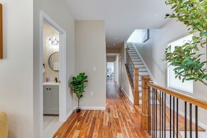 A hallway with wooden flooring, a staircase with a wooden railing, and a potted plant. - Luxe Newark Retreat w/ Rooftop Deck: Pets Welcome! (Newark)