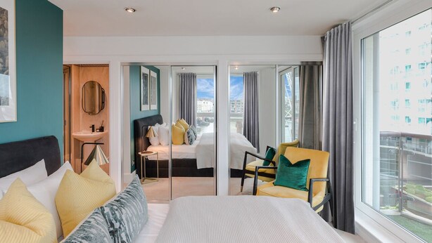 Une chambre d’hôtel moderne dotée d’un grand lit, d’un bureau, d’une chaise et d’un balcon avec vue.