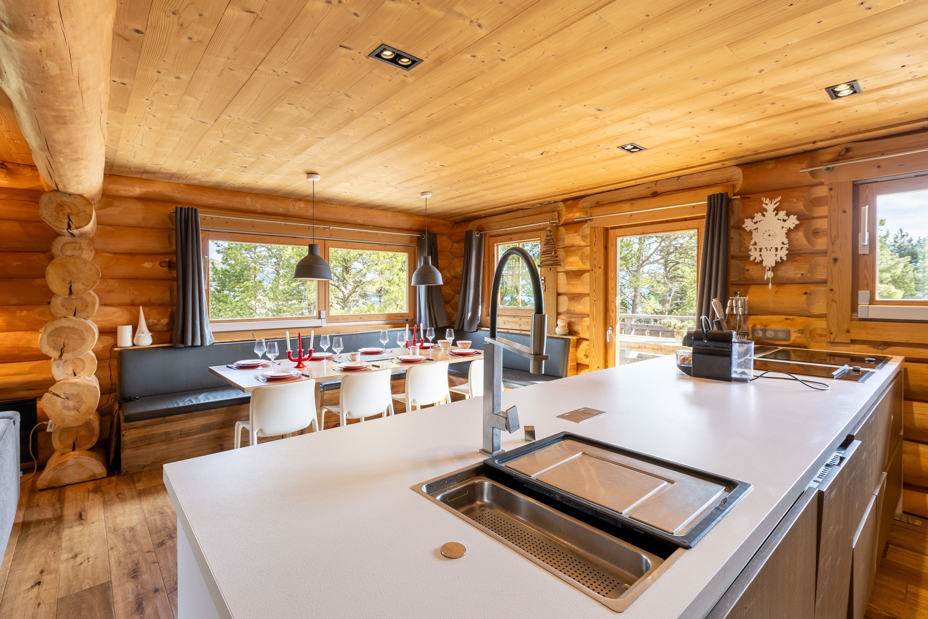 Een houten chalet van binnen met een keukenhoek, eettafel en zithoek.