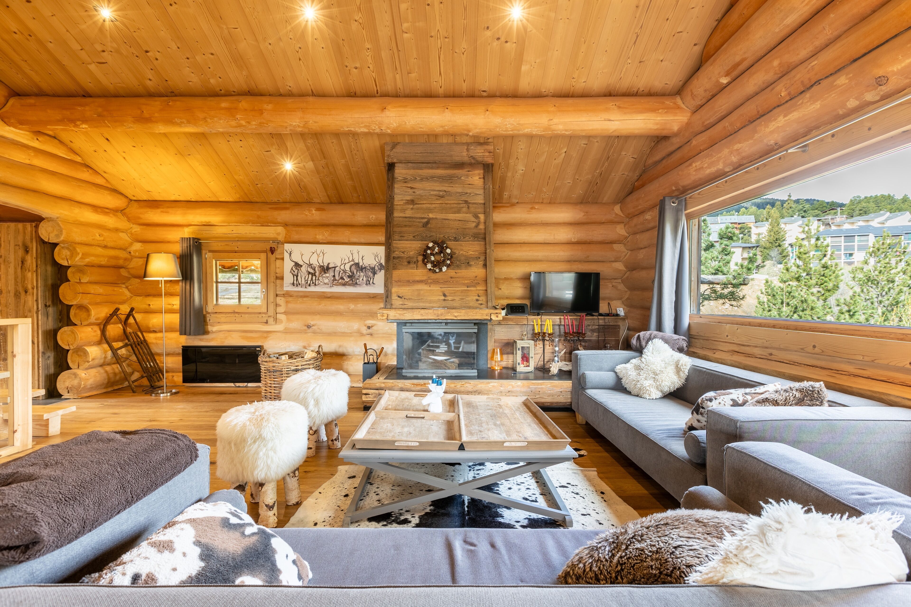 A log cabin interior with a sofa, a coffee table, a fireplace, and a TV.