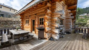 Eine Blockhütte mit einer Holzterrasse, einem Waschbecken und einem Tisch.