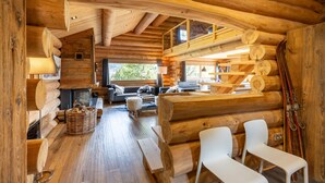 Ein Blockhaus-Interieur mit Kamin, Holzmöbeln und einem Schlafbereich auf der oberen Etage.