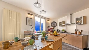A modern kitchen with a wooden island, stainless steel appliances, and a large window offering a view. - Maison Rioma - Grande maison à 200m de la plage (Plounéour-Trez)