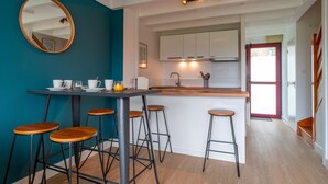 Una cocina moderna con una isla central, taburetes de bar y un espejo redondo en la pared.