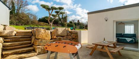 Patio esterno con tavolo da calcio, tavolo da picnic e parete in pietra.