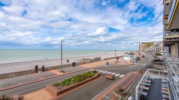 Une rue côtière avec vue sur la plage, une promenade piétonne et une chaussée réservée aux véhicules.