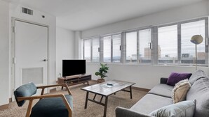 Una sala de estar moderna con televisor de pantalla plana, una mesa de centro, un sofá y una silla.