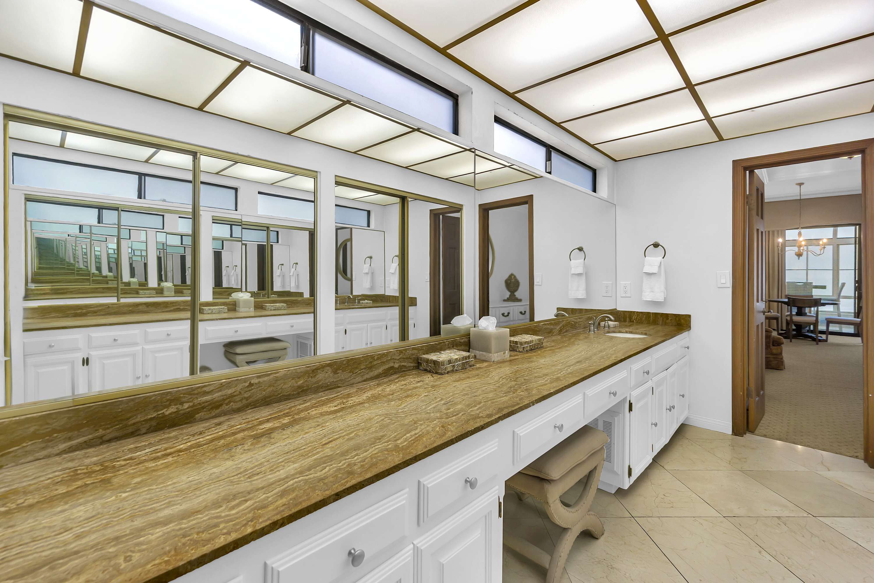 A modern bathroom with a long vanity, multiple mirrors, and a large window.