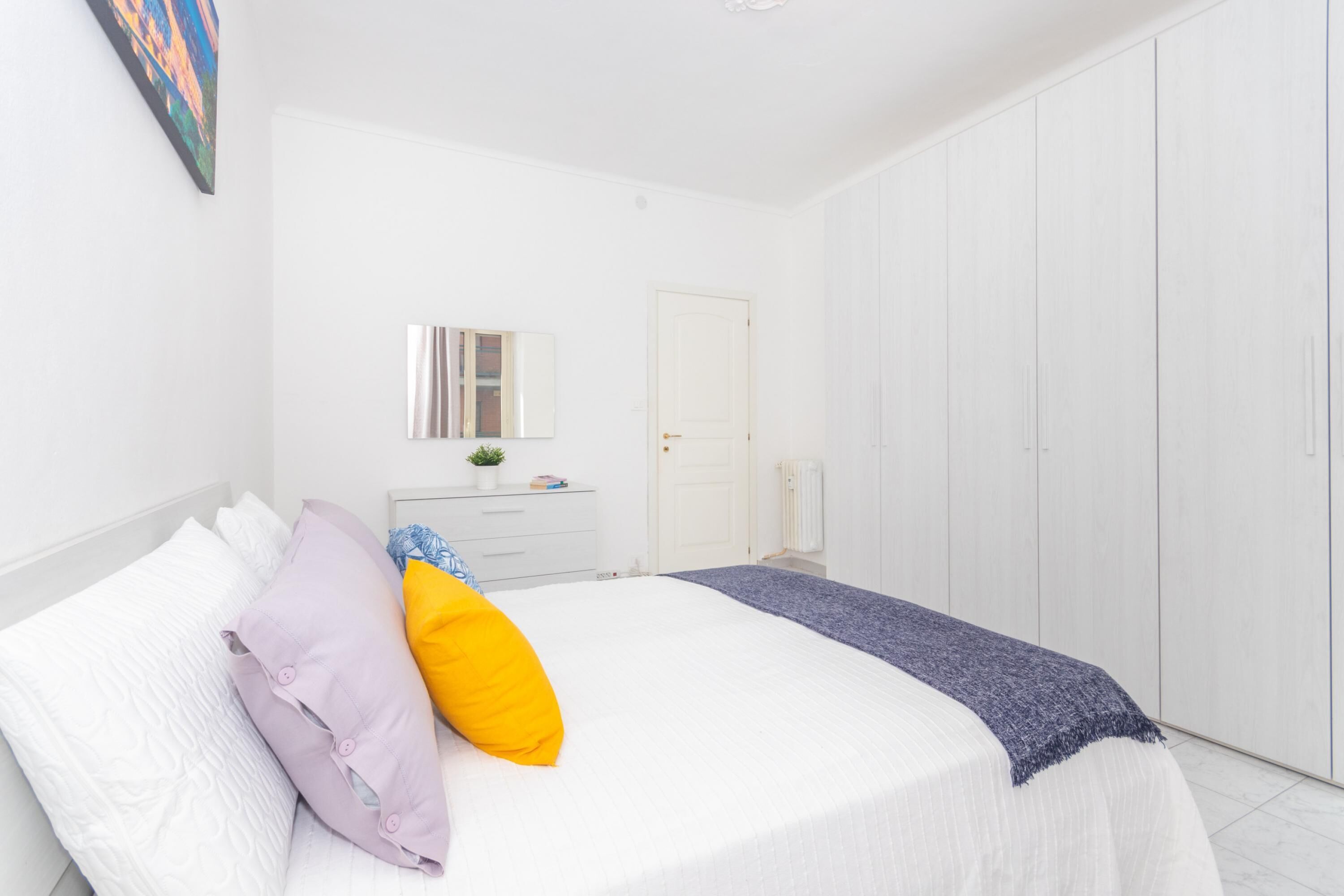 A bedroom with a bed, a dresser, a mirror, and a wardrobe.