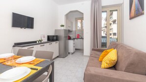 A compact living space with a kitchenette, dining area, and a sofa with cushions. - Casa Delia by Wonderful Italy (Turin)