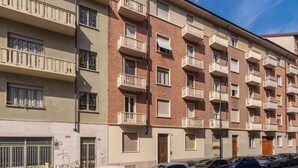 A multi-story residential building with balconies, a parking area, and a clear sky. - Casa Delia by Wonderful Italy (Turin)