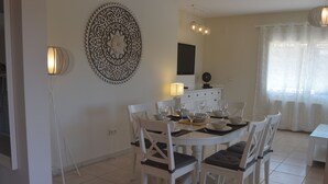 A dining area with a round table, white chairs, and a decorative wall piece. - Beautiful Villa Sunflower with private pool and garden, nearby the beaches. (Xabia)
