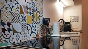 A kitchen with patterned tiles, a kettle, a coffee maker, and a refrigerator.