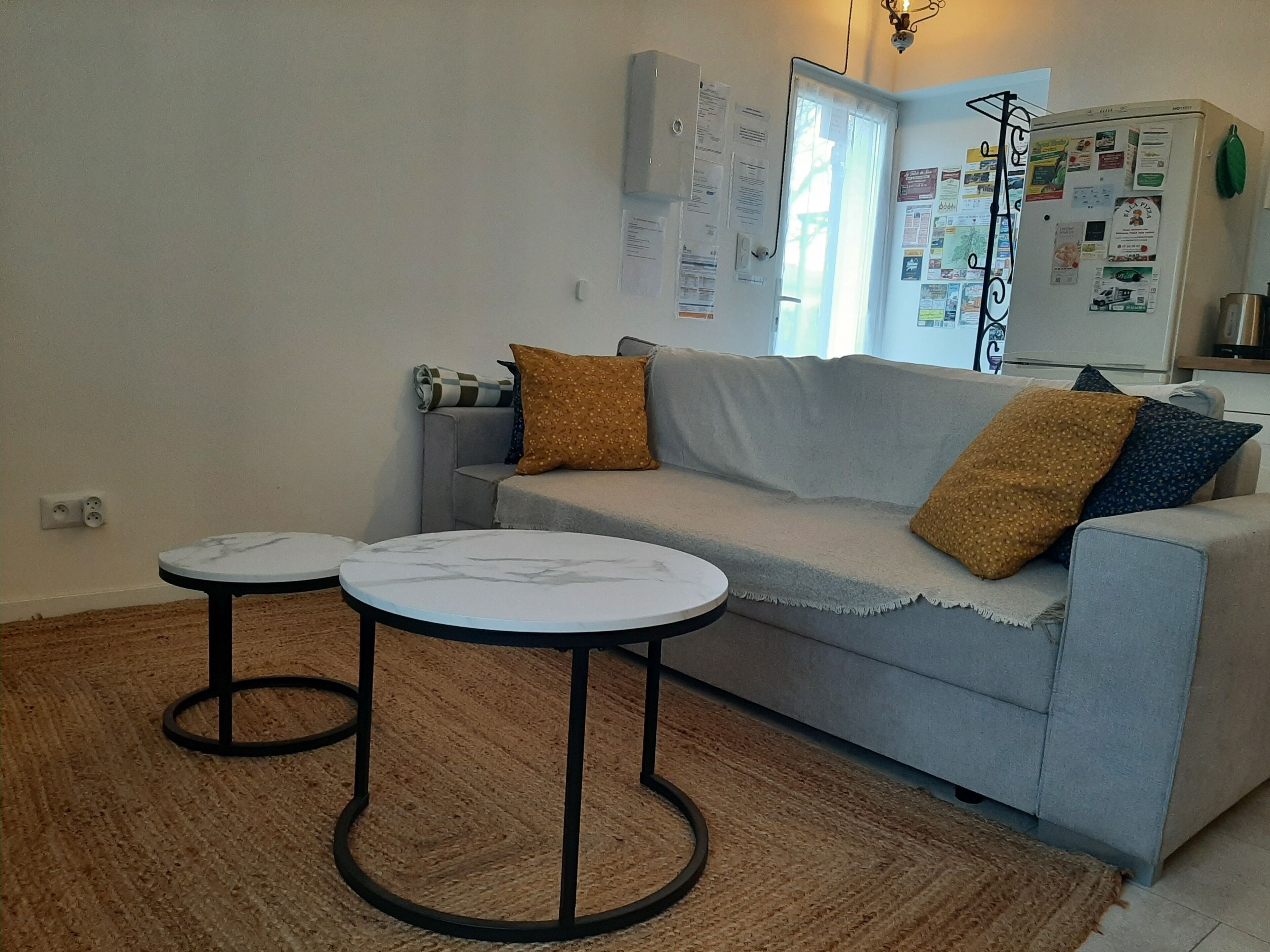 A living room with a grey sofa, two small round tables, and a brown rug.