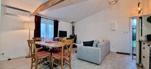 A cozy living room with a dining table, chairs, a sofa, and a fireplace. - Gîte de L'akwaba Logement T2 Buzet-sur-baïse 47160 - LOT ET Garonne (Buzet-sur-Baïse)