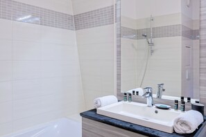 A modern bathroom with a white sink, a mirror, and a shower.