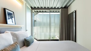 Habitación de hotel con cama, un cuadro en la pared y vistas al balcón exterior.