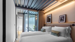 Una habitación de hotel moderna con dos camas, un ventanal grande y un techo de diseño único.