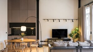 A modern living room with a wooden dining table, sofa, and TV. - Feel Porto Matosinhos City Flat III (Matosinhos)