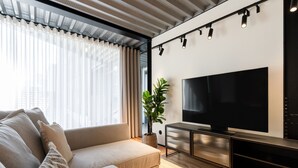 Un salon moderne avec un canapé, un téléviseur à écran plat et une plante en pot.